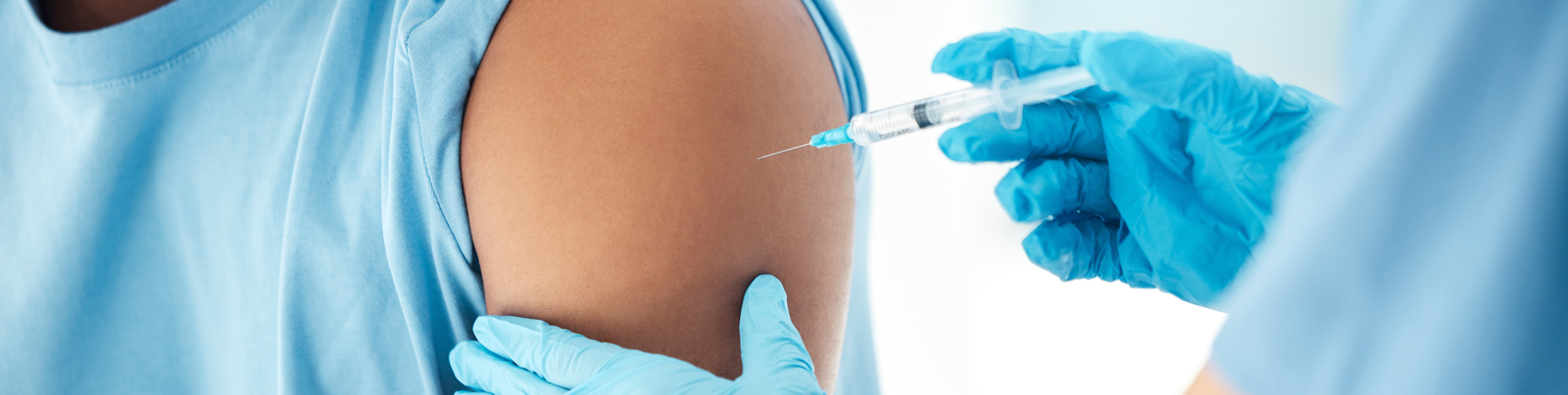 Closeup of a health professional administering a shot to a patients arm.