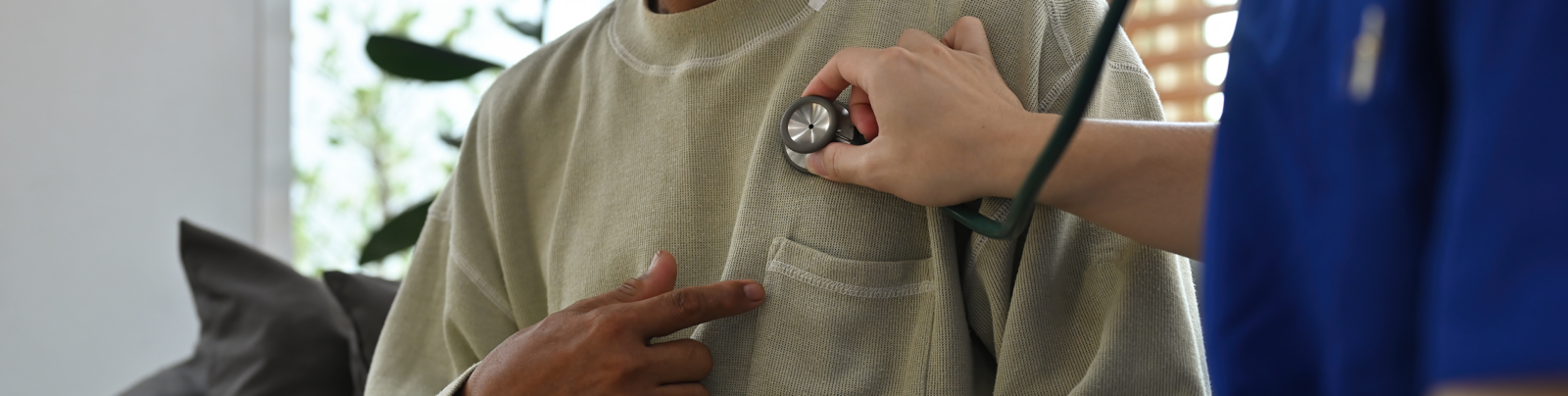 A doctor using a stethoscope over a mans chest.